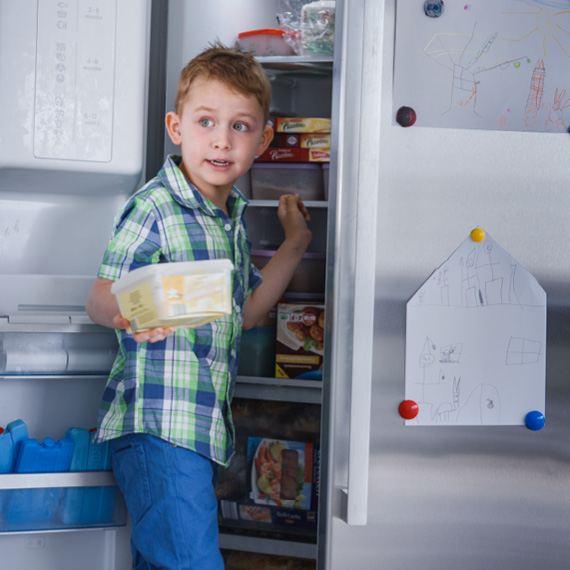 Ein Kind steht vor dem offenen Kühlschrank