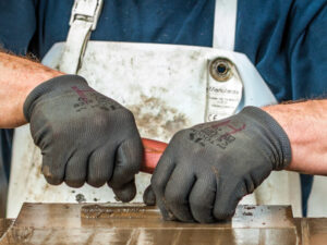 Hände eines Mannes in Arbeitshandschuhen beim Bau eines Ofens