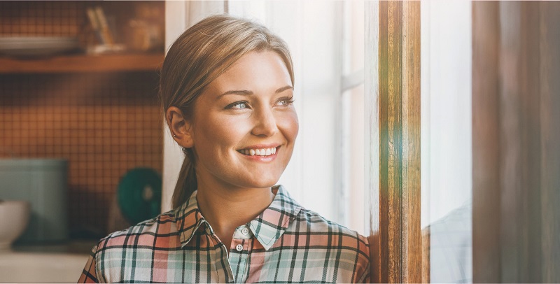 Frau lächelt aus einem Fenster hinaus