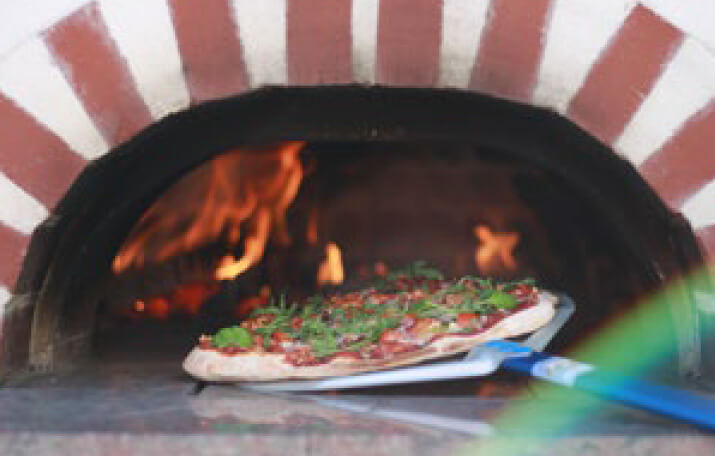 Pizza wird in einen Backofen geschoben